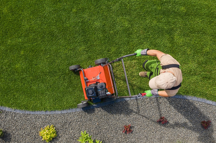 a man is using a lawn mower to cut grass.