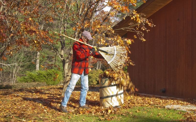 a man with a broom and a bucket of leaves.