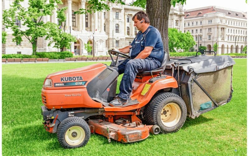 a man riding on the back of a lawn mower.