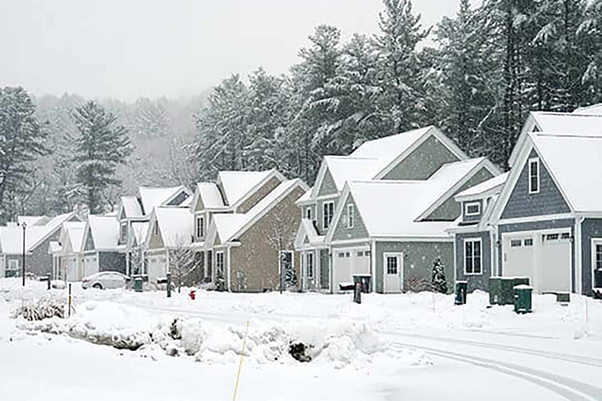 A row of houses covered in snow on a snowy day.
